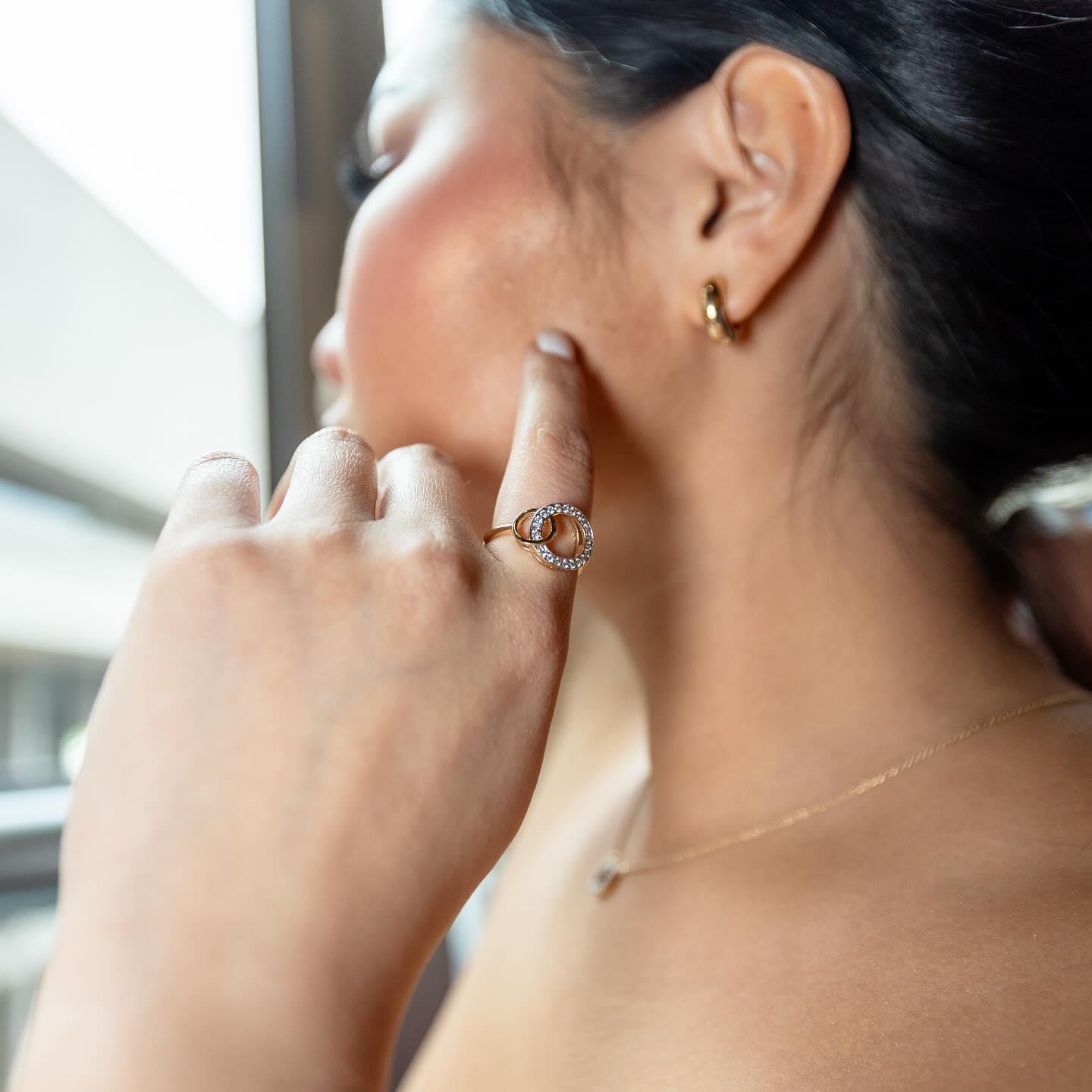 Profile portrait wearing interlocking ring, hoop earring, and chain