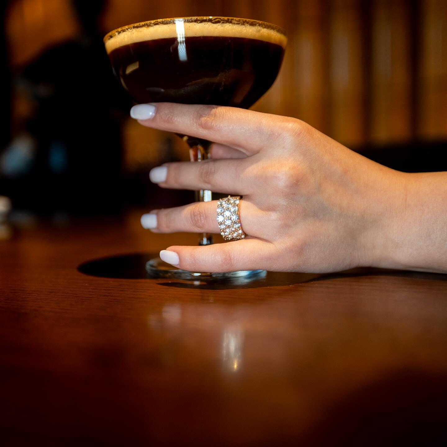Wide diamond pavé ring on a hand holding an espresso martini
